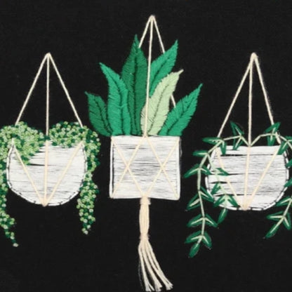 Embroidered design of three hanging planters with green leaves on a black background