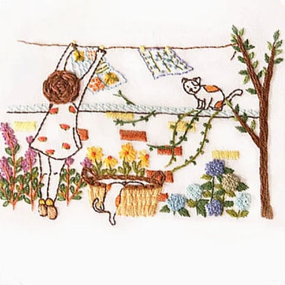 Embroidery of a child hanging laundry on a line with a cat and flowers in the background