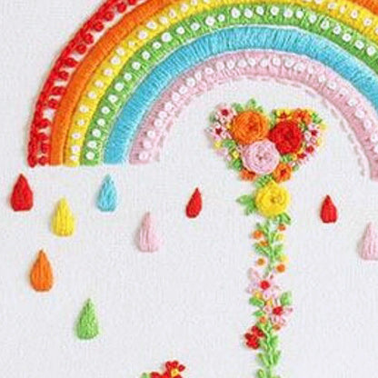 Colorful crochet rainbow with flowers and raindrops on a white background