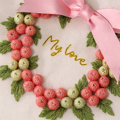 Embroidered wreath with berries and leaves and a pink ribbon, with 'My love' embroidered in gold.