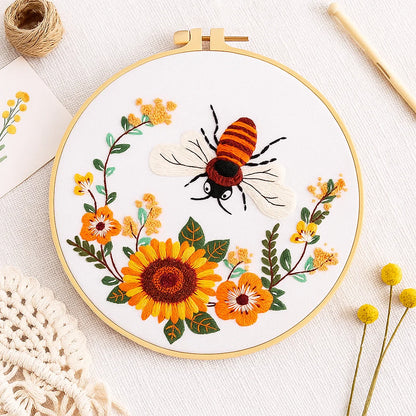Embroidery hoop with a bee and floral design on a white background