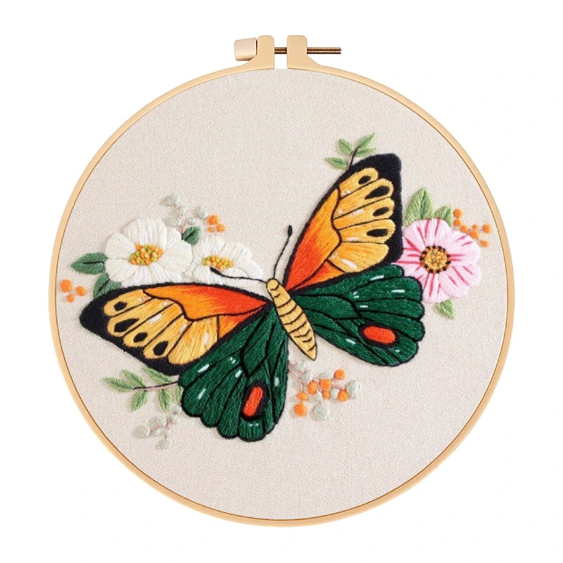 Embroidery hoop with a colorful butterfly and floral design on beige fabric.