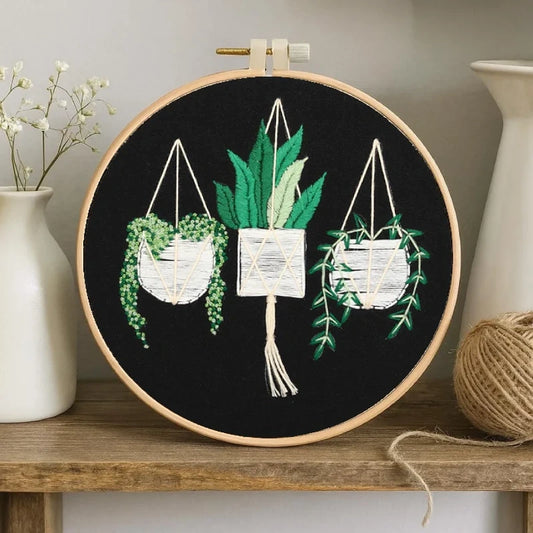Embroidery hoop with plant-themed design on a wooden shelf.