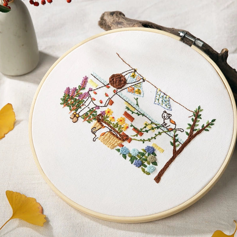 Embroidery hoop with floral and nature-themed embroidery on a light background