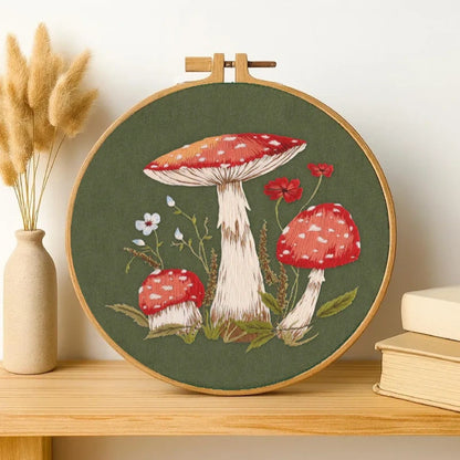 Embroidery hoop with mushroom design on a wooden shelf.