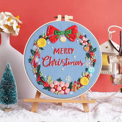 Set against a cheerful blue background, this design features a festive red bow and “Merry Christmas” message surrounded by golden ornaments, pink blossoms, gingerbread men, and delicate snowflakes. It captures the warmth and joy of the holiday season — perfect for Christmas home décor or as a heartfelt handmade gift for someone special.