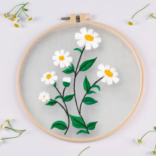 Embroidery hoop with white flowers and green leaves on a light gray background
