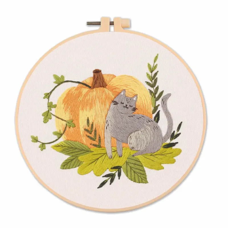 Embroidery hoop with a cat and pumpkin design on a white background