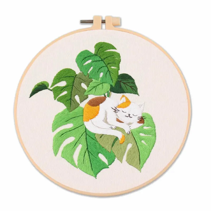 Embroidery hoop with a cat and leaf design on a white background